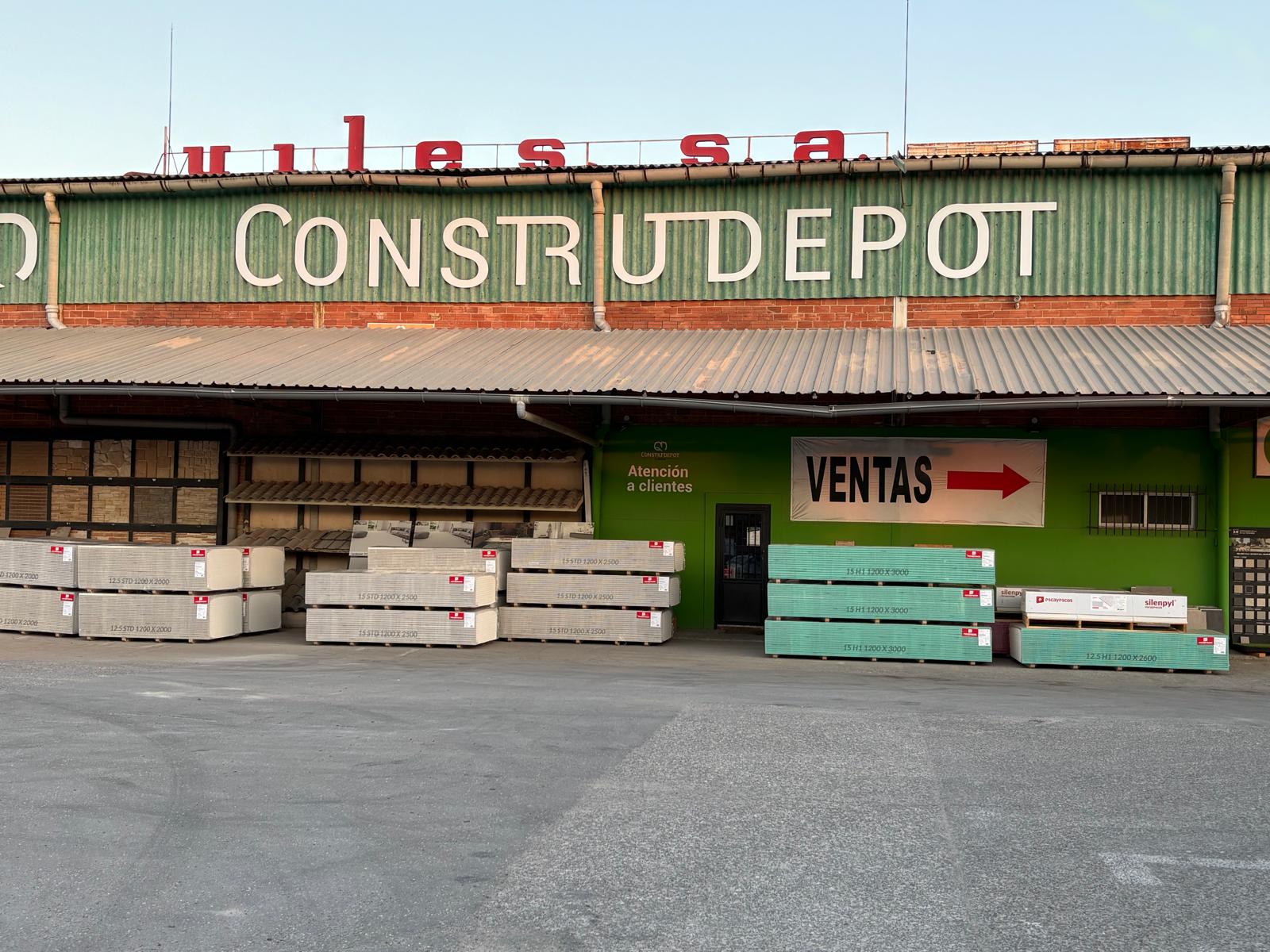 Fachada real de Construdepot by Quiles en Elche, con palés de Pladur y materiales en la entrada